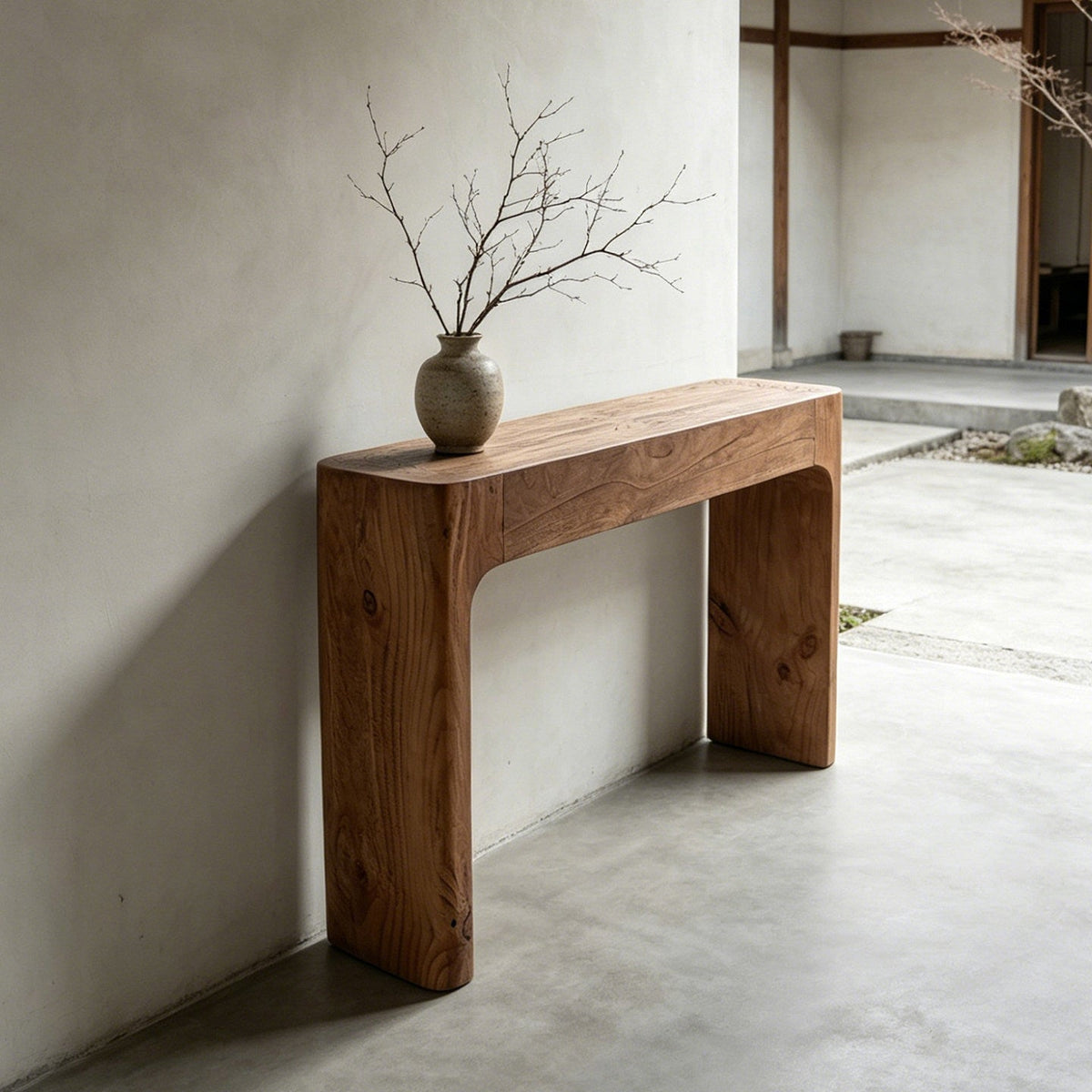 Brown wood-grain console table with broad sides and rounded inner corners, styled with a branch-filled vase.