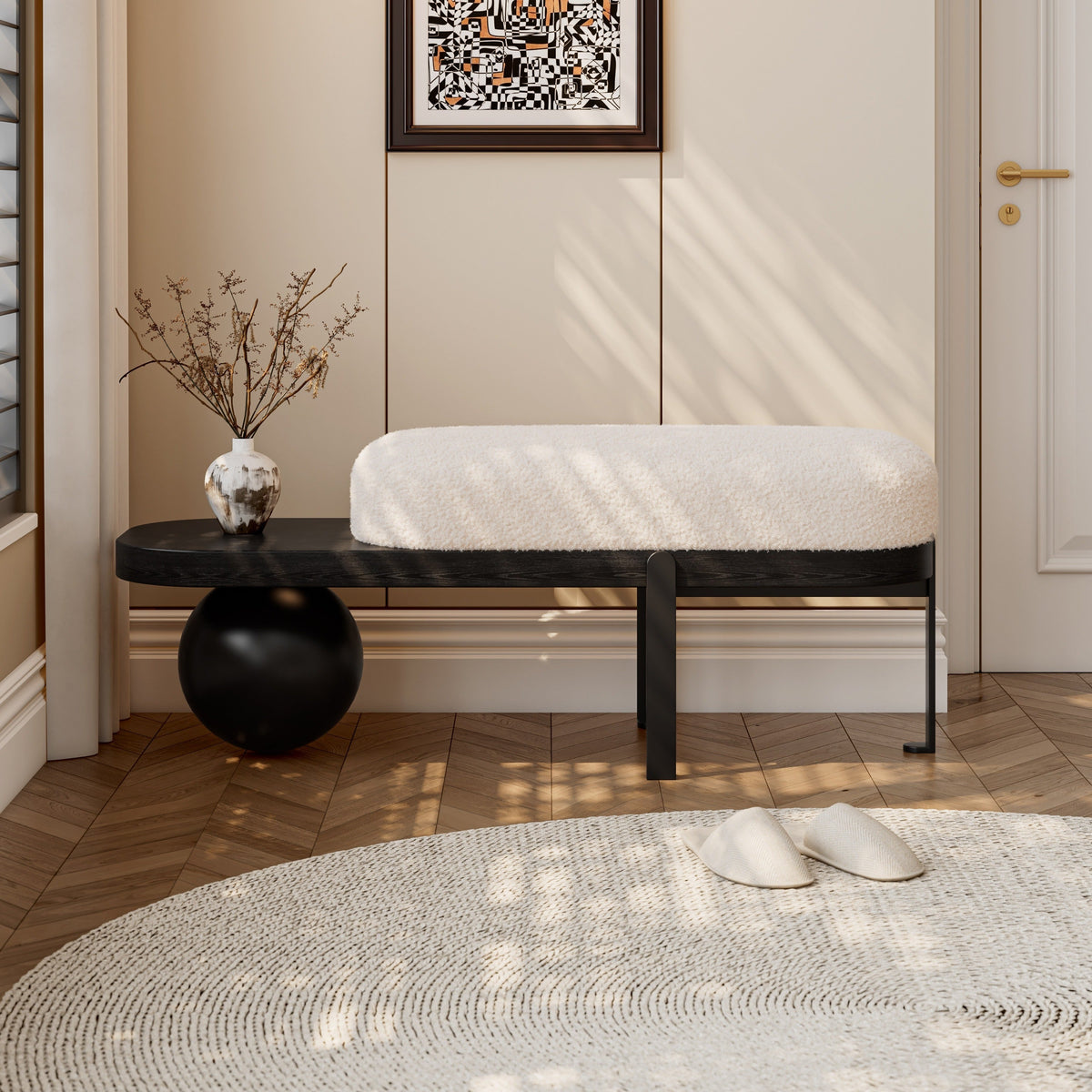 Cream upholstered entryway bench with a black frame, exposed side shelf and spherical support.