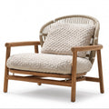 A modern outdoor lounge chair featuring a natural wood frame, woven rattan backrest, and textured cream-colored seat and back cushions, shown on a white background.