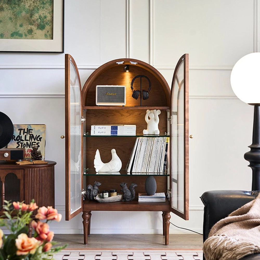 Brown arched cabinet with both doors open, showing glass shelves, books, ornaments and an interior light.
