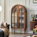 Angled room view of the brown arched glass cabinet with decorative door framing.