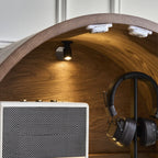 Close-up inside the arched cabinet showing its ceiling light above a speaker and headphones.