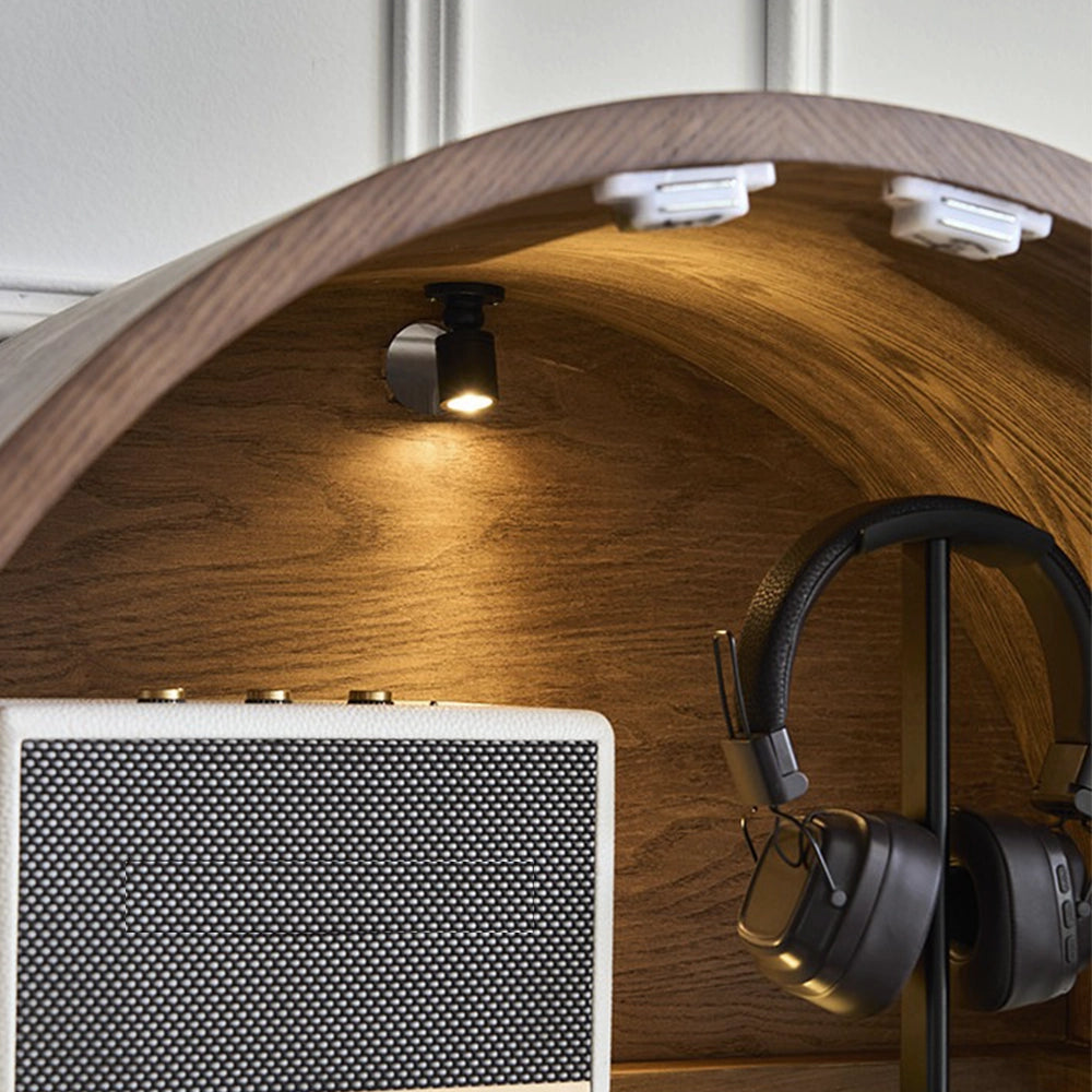 Close-up inside the arched cabinet showing its ceiling light above a speaker and headphones.