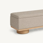Close-up of the beige bench's padded lid corner, upholstered side and cylindrical foot.