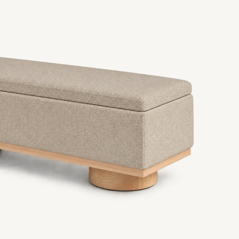 Angled detail of the beige bench's rectangular end panel and short round support foot.
