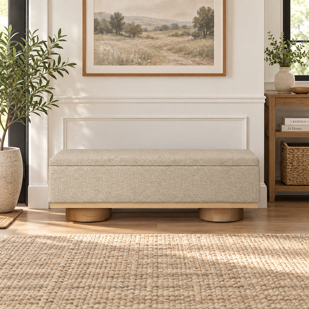 Front view of the beige box-shaped bench with a narrow wood-tone base and cylindrical feet.