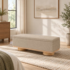 Beige upholstered storage bench with a rectangular padded top and short round wood-tone feet.