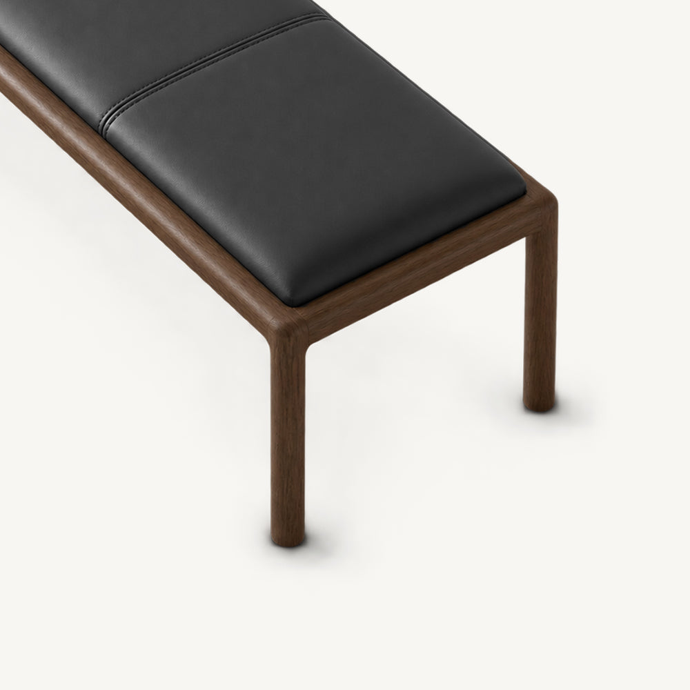 Overhead detail of the bench's black stitched cushion above a rounded wood-tone frame corner.