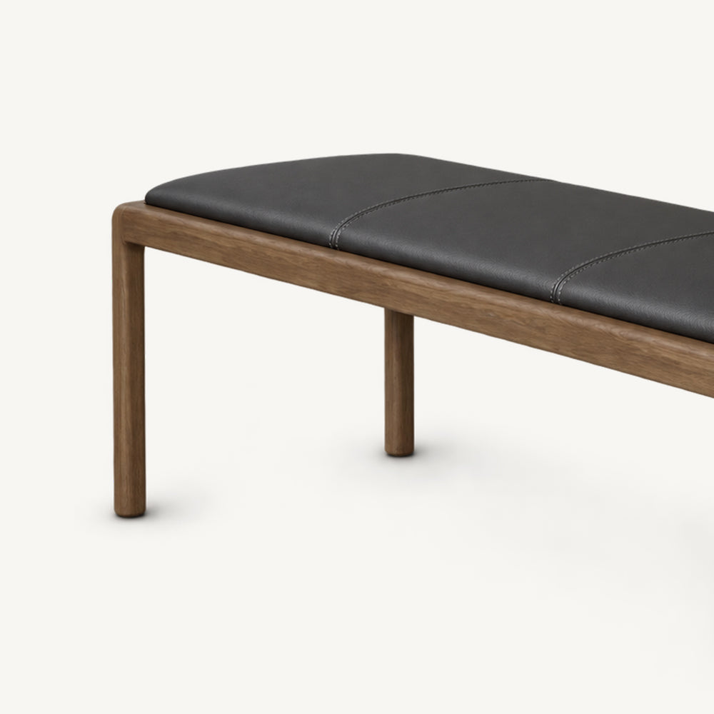 Close-up of the black bench cushion, brown frame and left pair of slim legs.