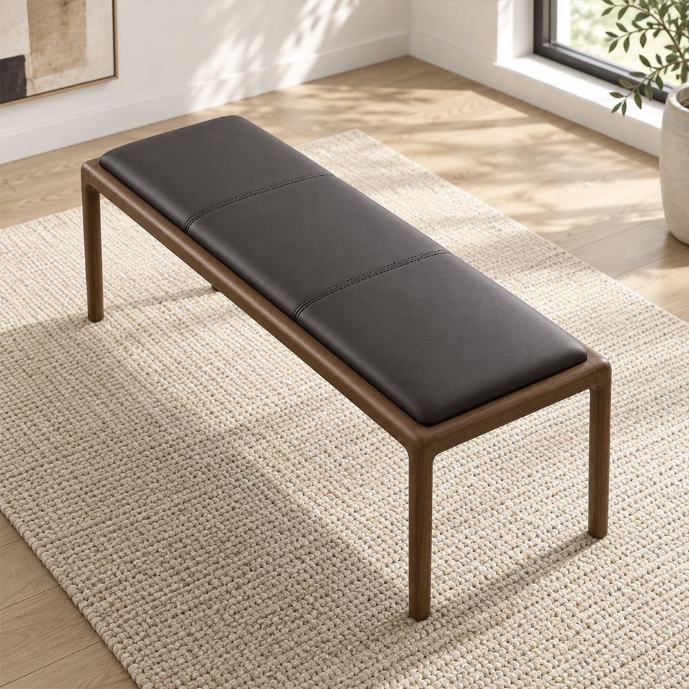 Overhead angled view of the bench's black stitched cushion and rounded brown frame.