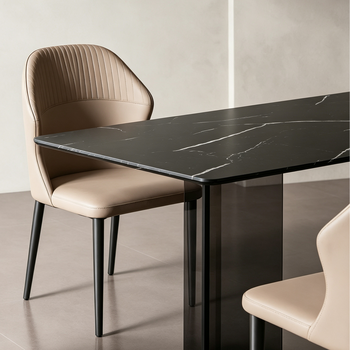Angled detail of the black veined dining table corner beside a beige upholstered chair.