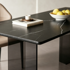 Close-up of the dining table's dark top with pale veins and a rounded corner.