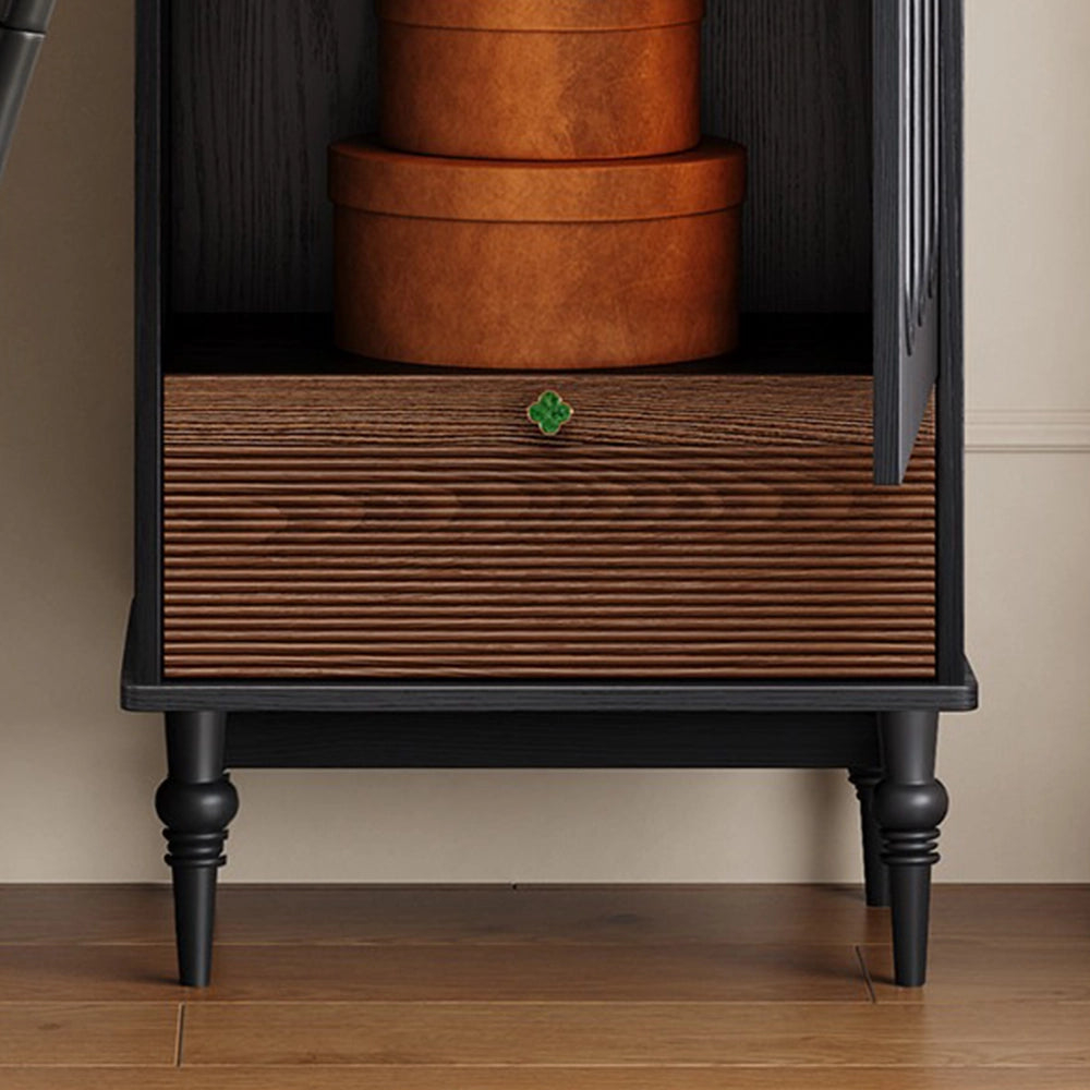 Close-up of the cabinet's brown textured drawer front, green knob and black turned legs.