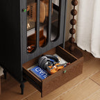 Open lower drawer of the black display cabinet holding headphones, books and small items.