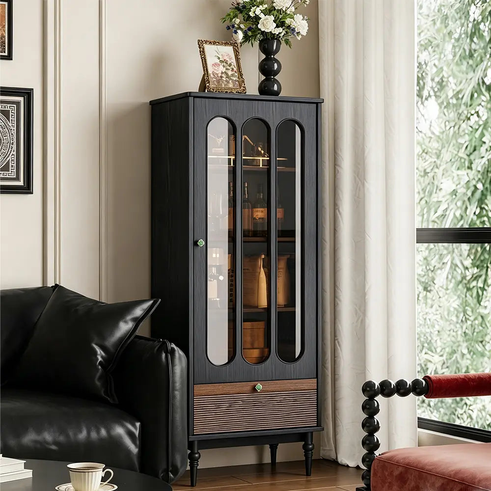 Tall black display cabinet with three elongated glass panels, a brown lower drawer and turned legs.