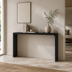 Black narrow console table with slab sides, styled with a vase and books beneath artwork.