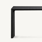 Close-up of the black console table's inner corner and side support beneath its narrow top.