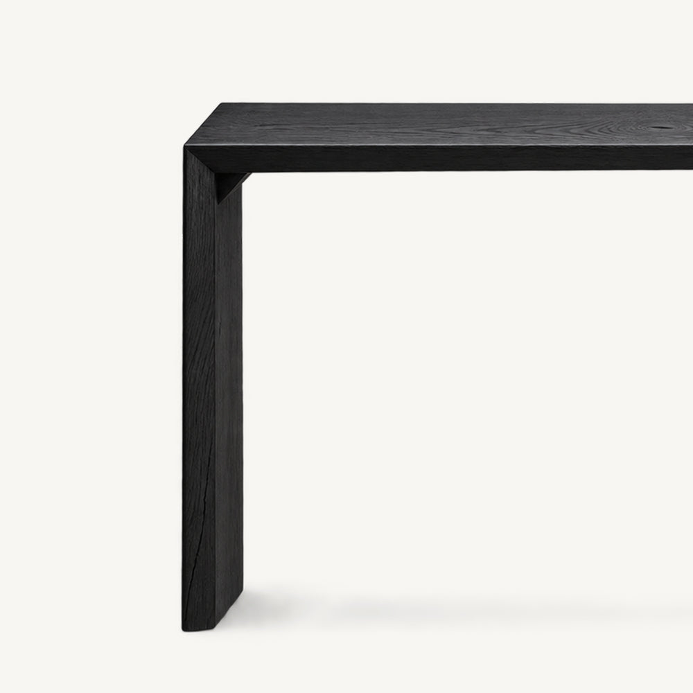 Close-up of the black console table's inner corner and side support beneath its narrow top.