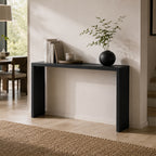Angled view of the black slab console table against a pale entryway wall.