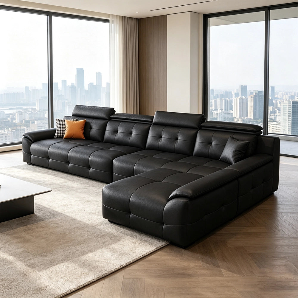 Black tufted sectional sofa with a chaise and padded headrests in a bright room with city views.