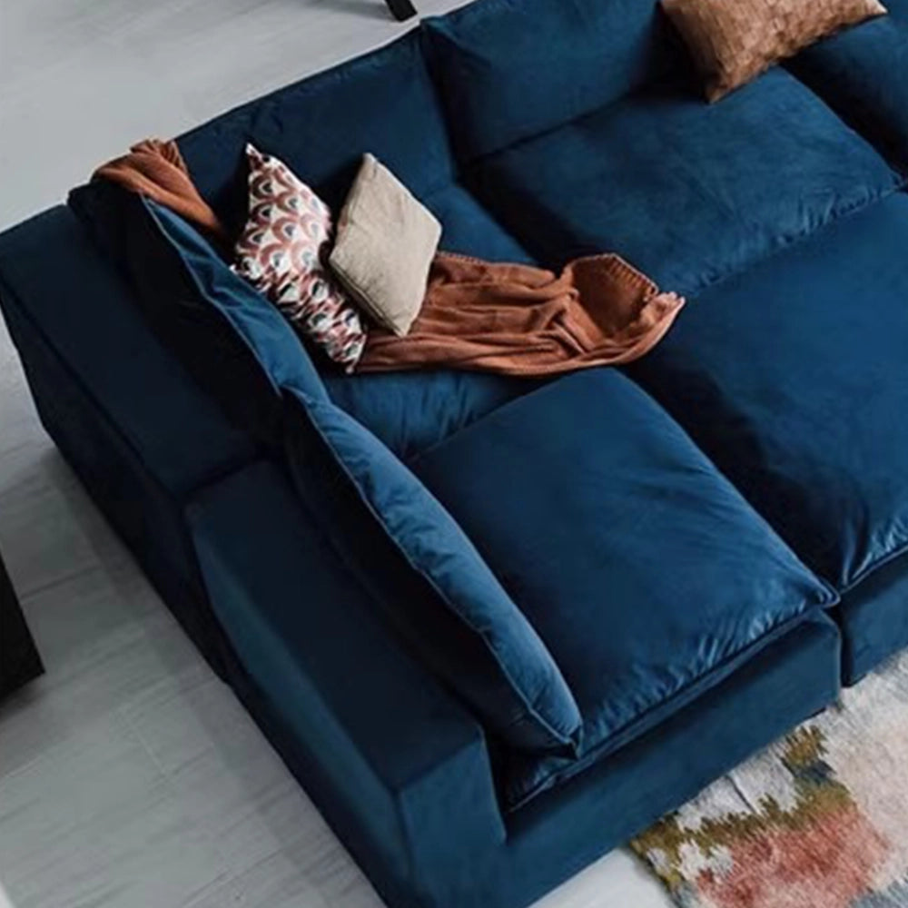 Detail of the blue modular sofa's left corner and padded arm cushions.