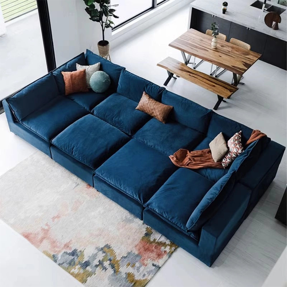 Deep blue modular sofa with a broad cushioned seating area and orange, cream and round teal accent pillows, viewed from above.