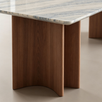 Close-up of the dining table's curved brown panel base beneath the rounded corner of the veined top.