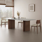 Blue-gray veined dining table with curved wood-tone bases beside a window in a neutral dining room.