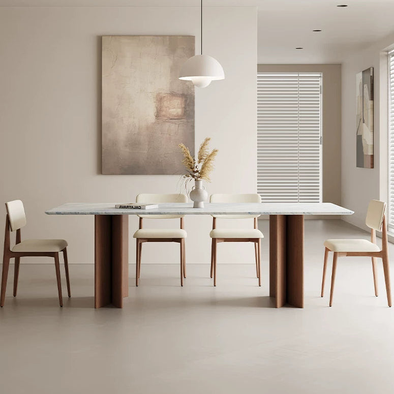 Rectangular dining table with a blue-gray veined top and two brown panel bases, surrounded by cream upholstered chairs.