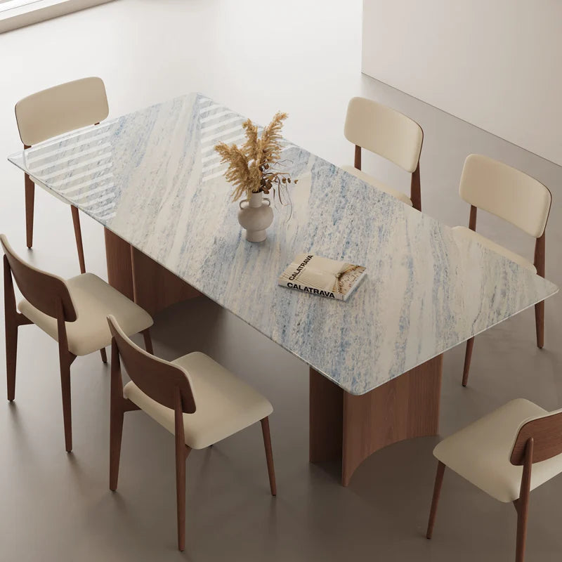 Overhead angled view of the dining table's pale blue-gray veined top, rounded corners and surrounding chairs.