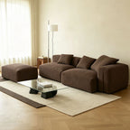 Brown modular sofa shown with its ottoman on the left as pictured and loose cushions across the back.