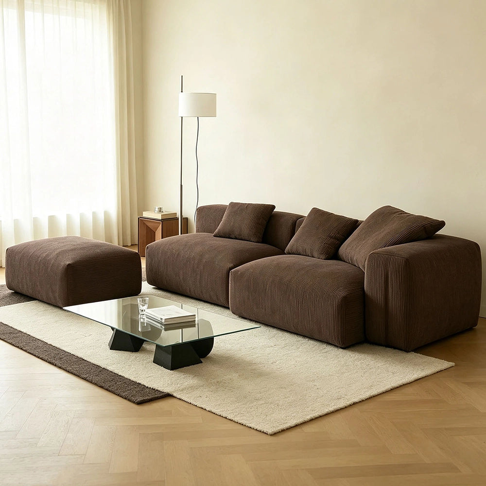 Brown modular sofa shown with its ottoman on the left as pictured and loose cushions across the back.