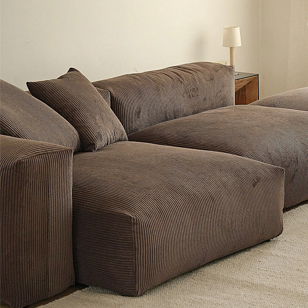 Close-up of the brown sofa's ribbed upholstery, deep seat modules and loose cushions.