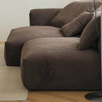 Side detail of the brown modular sofa showing deep seats and ribbed cushion fabric.