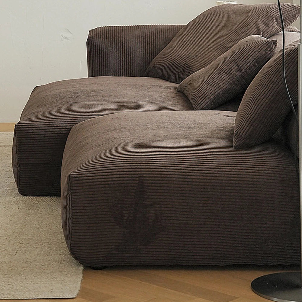 Side detail of the brown modular sofa showing deep seats and ribbed cushion fabric.