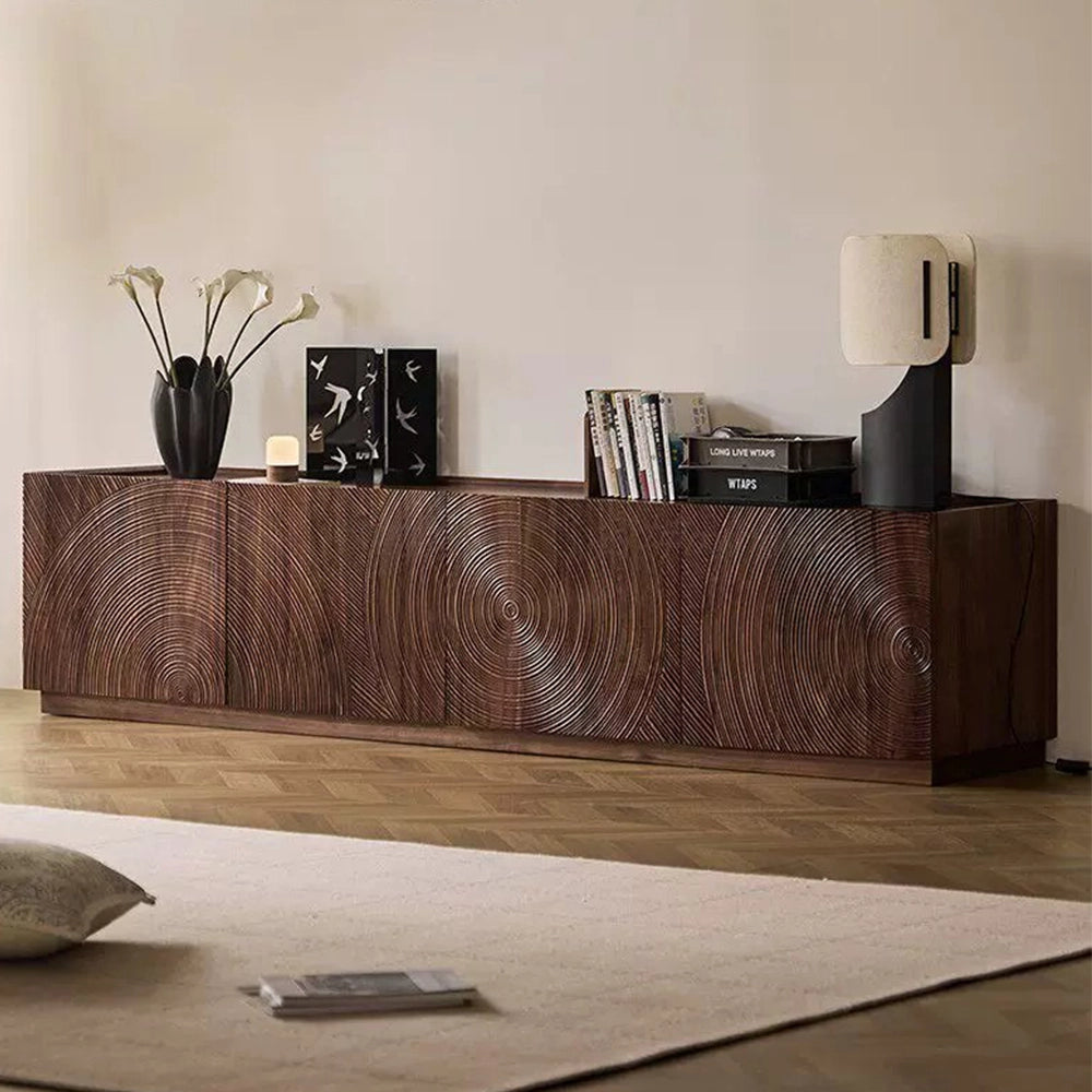 Angled view of the low brown TV cabinet with sculpted circular door patterns.
