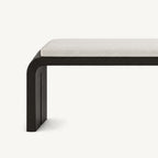 Close-up of the cream bench cushion above a rounded black frame corner and side support.