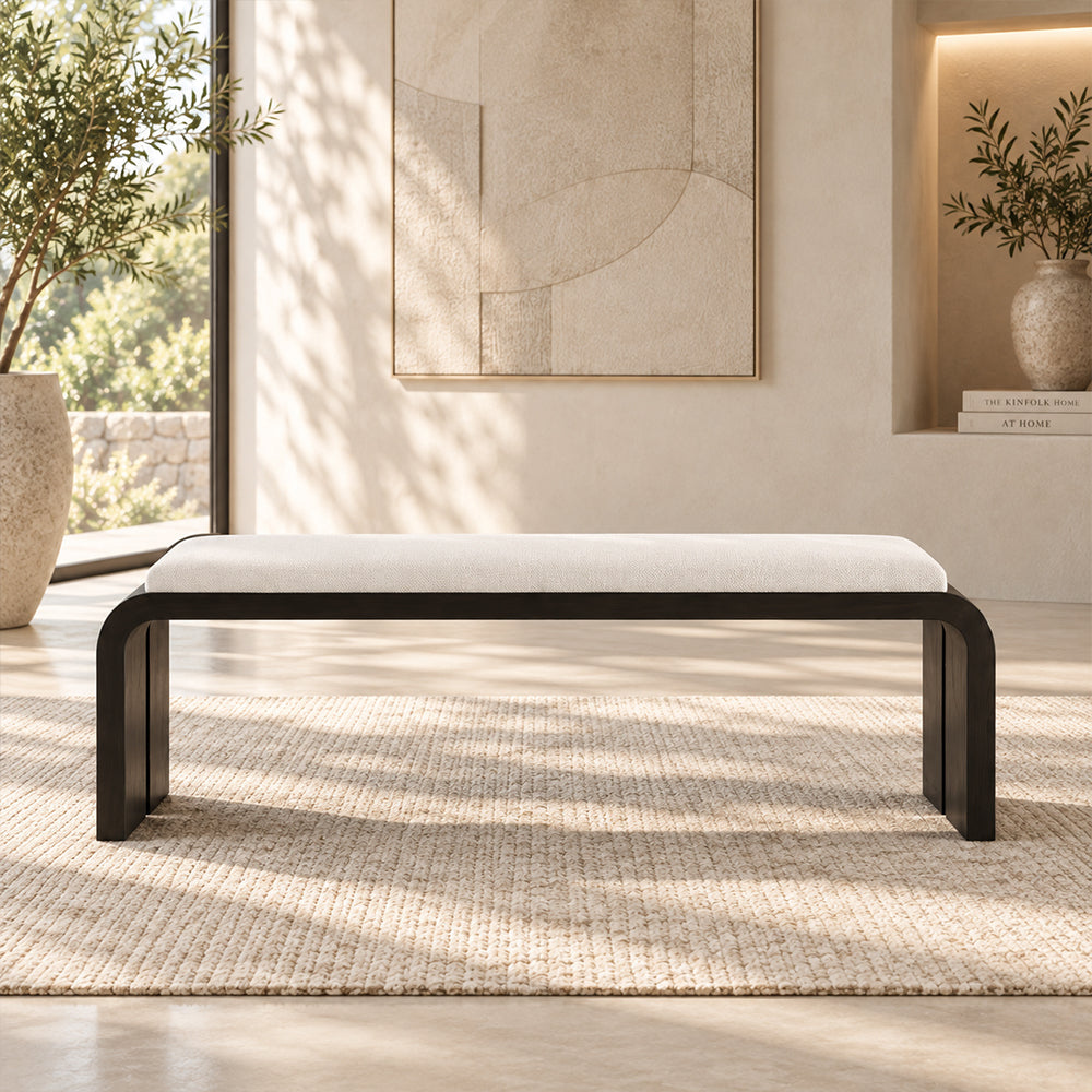 Front view of the cream-cushioned black bench with rounded outer corners and slab legs.
