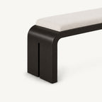 Angled detail of the bench's black slab leg with a narrow vertical slot beneath the cream cushion.