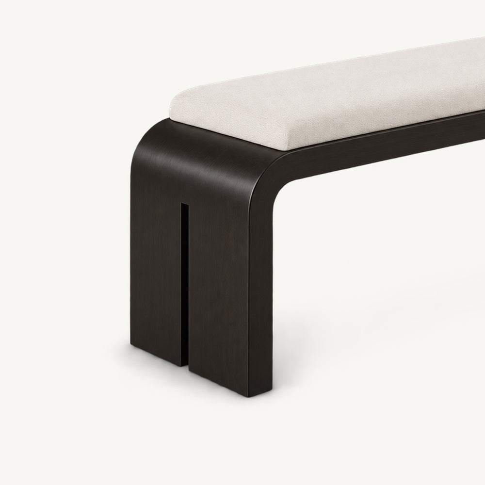 Angled detail of the bench's black slab leg with a narrow vertical slot beneath the cream cushion.