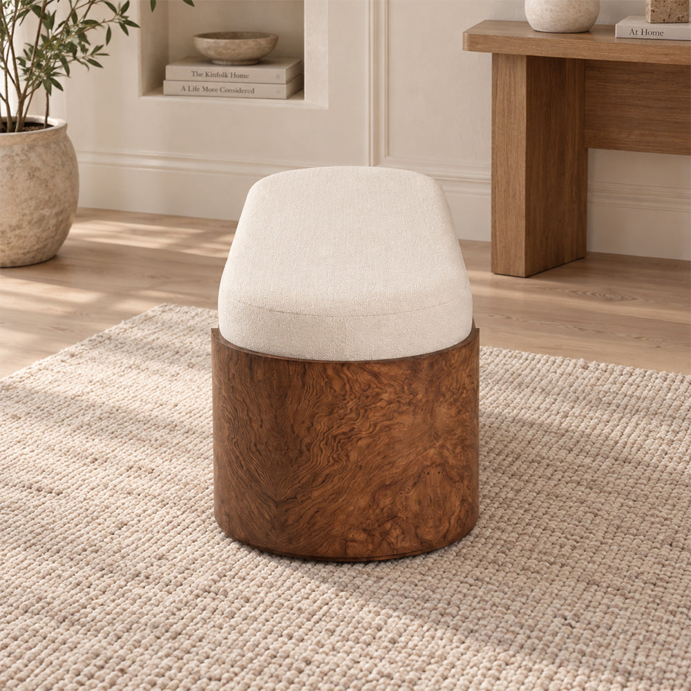 End view of the cream bench showing its curved cushion and rounded brown support with swirling grain.