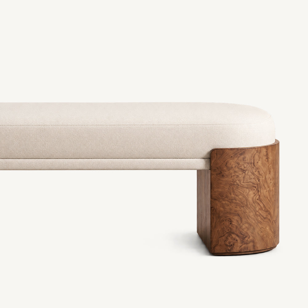 Close-up of the cream bench's seat edge, upholstered crossbar and brown end support.