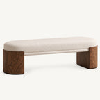 Long cream upholstered bench with curved brown end supports on a white background.