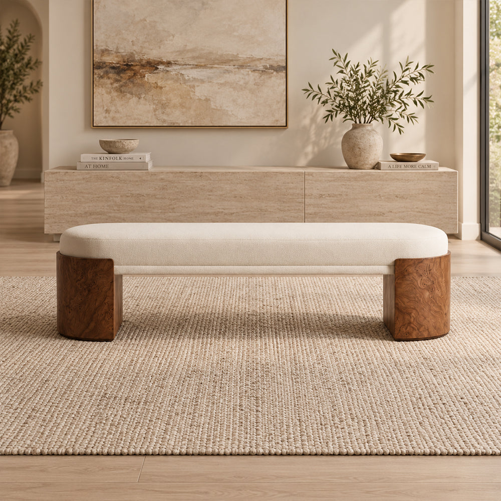 Front view of the cream upholstered bench with two broad rounded brown supports.
