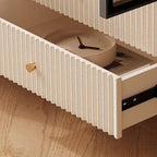 Close-up of an open cream fluted drawer with a gold-tone knob and a clock inside.