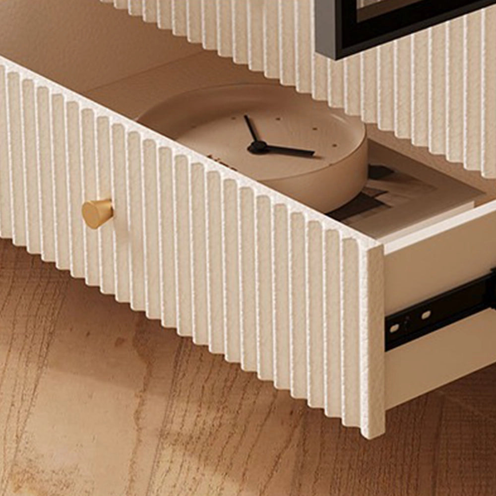 Close-up of an open cream fluted drawer with a gold-tone knob and a clock inside.