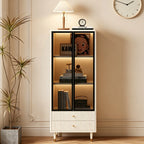 Cream display cabinet with black-framed glass doors, illuminated shelves and two fluted lower drawers.