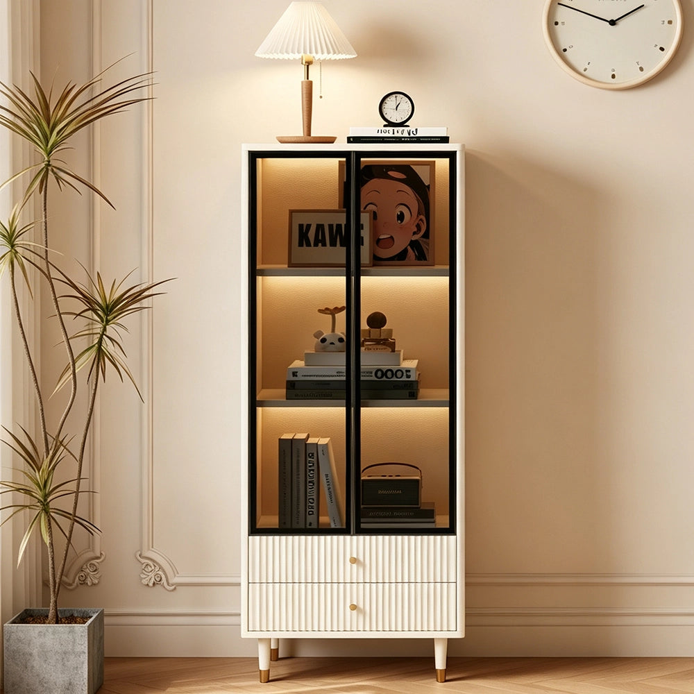 Cream display cabinet with black-framed glass doors, illuminated shelves and two fluted lower drawers.