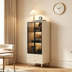 Cream glass display cabinet standing beside a chair, with illuminated shelves holding books and ornaments.