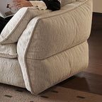 Close-up of the cream sofa bed's padded outer arm, seams and loose arm cushion.